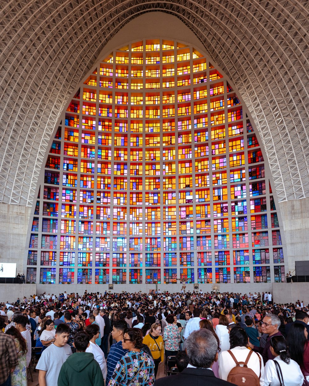 a large group of people standing in front of a large stained glass window