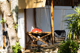 A cozy backyard scene featuring a verdaluxe outdoor bar set surrounded by lush greenery and a floral yard banner fluttering gently in the breeze.