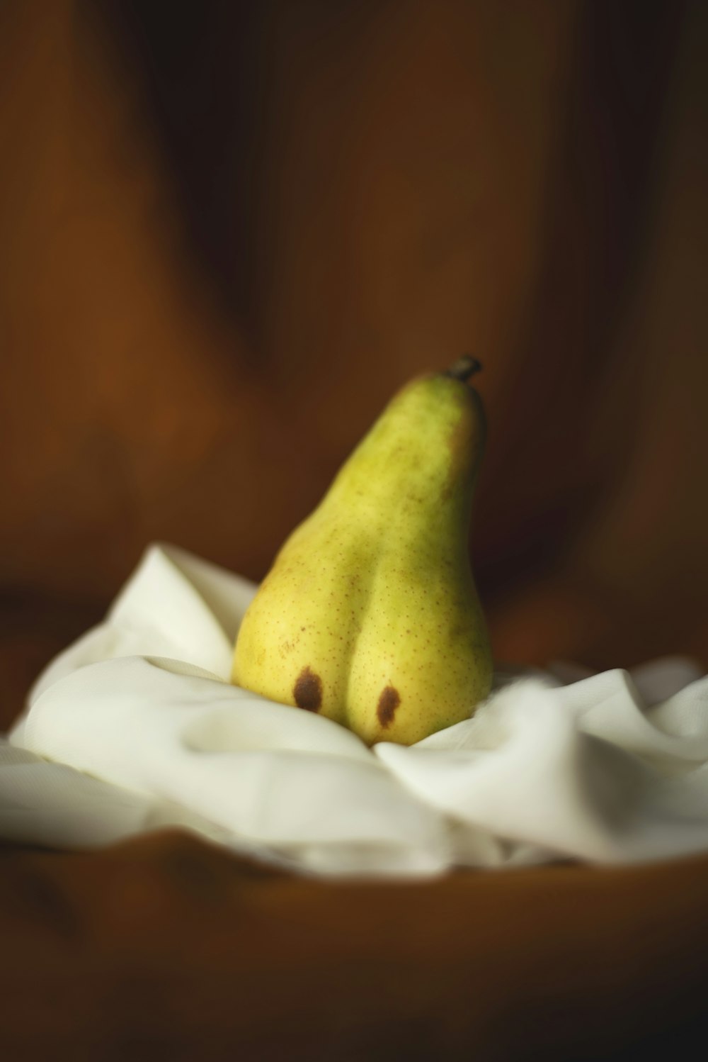 a yellow pear sitting on top of a white cloth