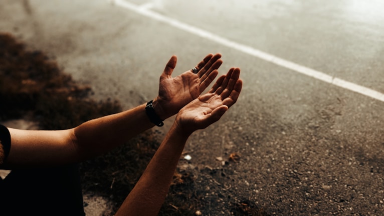 Close-up of hands shaking in front of a transport truck, symbolizing trust.
