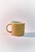 a yellow coffee cup sitting on top of a white table