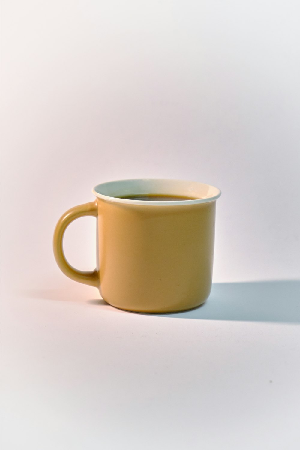 a yellow coffee cup sitting on top of a white table