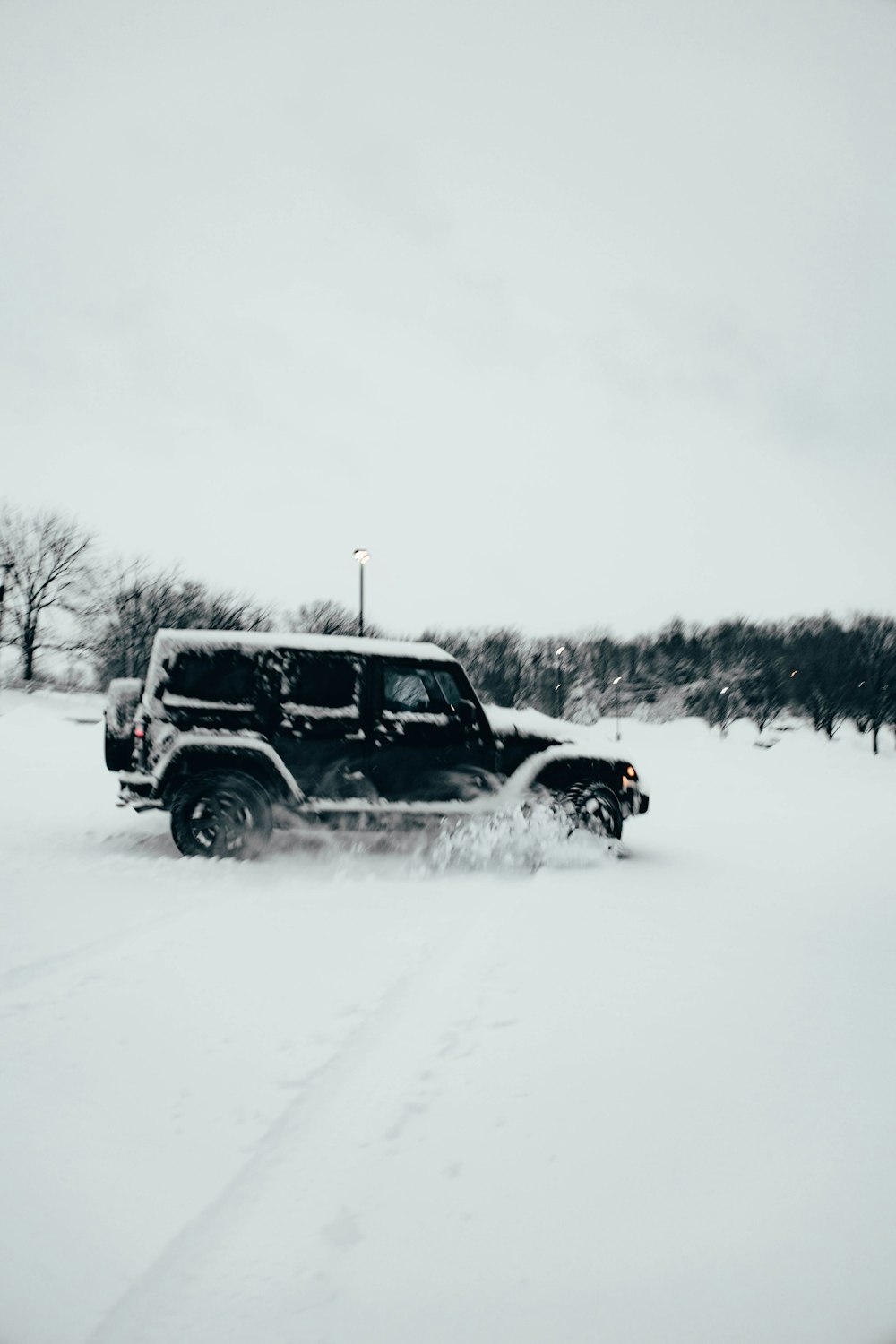 um jipe dirigindo através de um campo coberto de neve