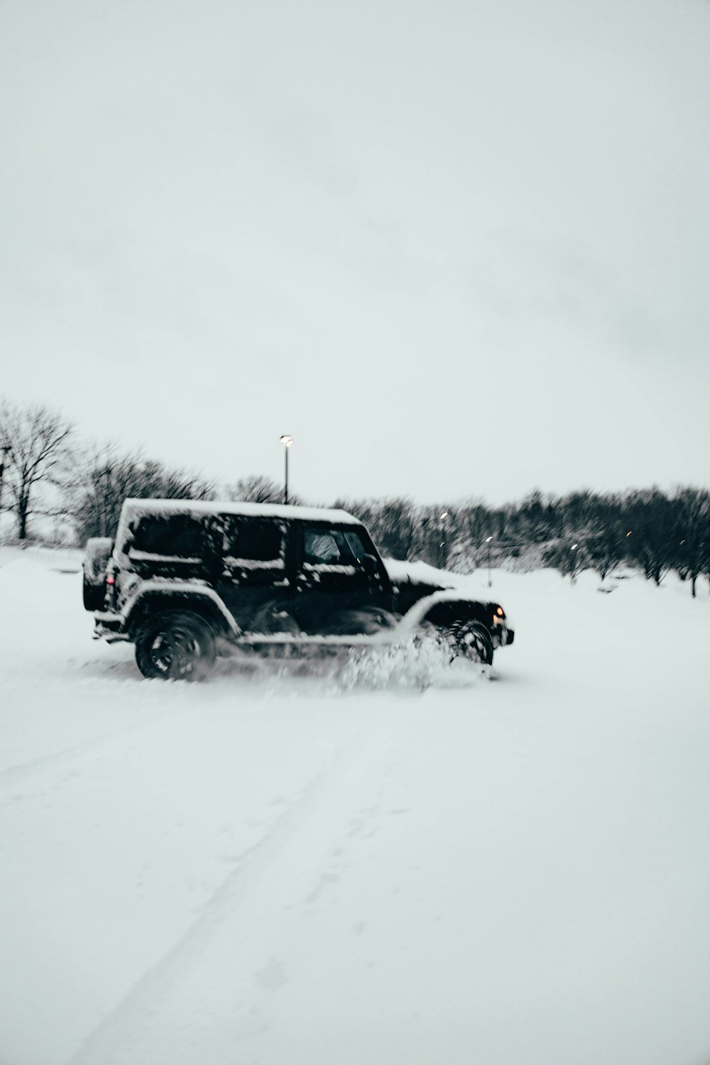 a jeep driving through a snow covered field