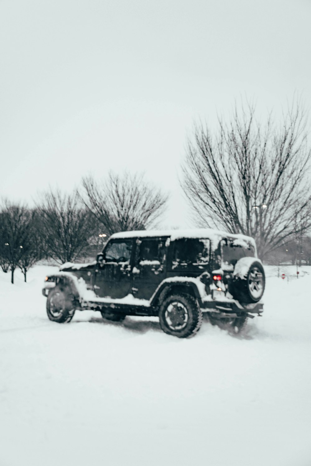 a jeep driving through a snow covered field