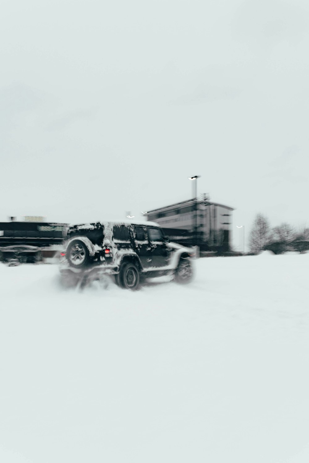 a black truck driving down a snow covered road