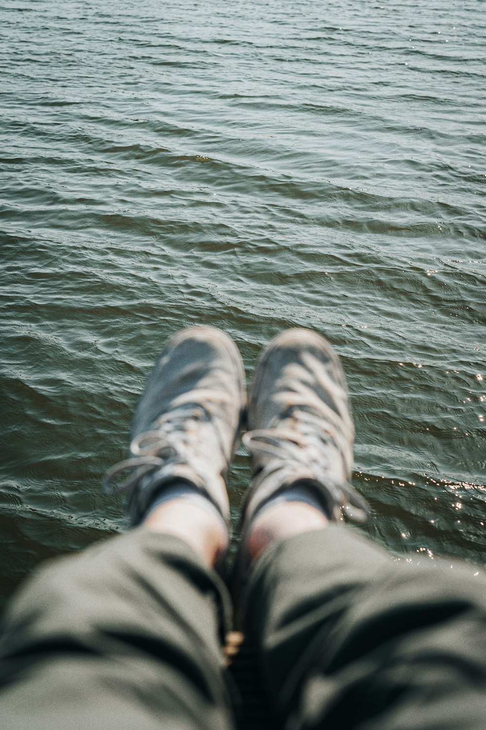 a person's feet in the water with a boat in the background