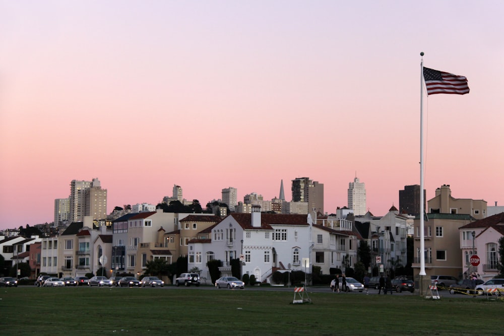 a large american flag flying in front of a city