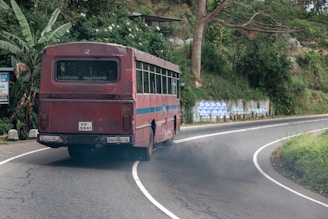 a pollutiong red bus driving down a curvy road