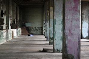 Wide shot of an empty industrial hall with scattered debris and muted colors.