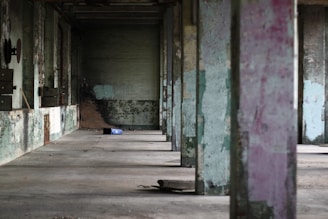Wide shot of an empty industrial hall with scattered debris and muted colors.