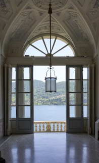 an open door leading to a balcony with a view of a lake