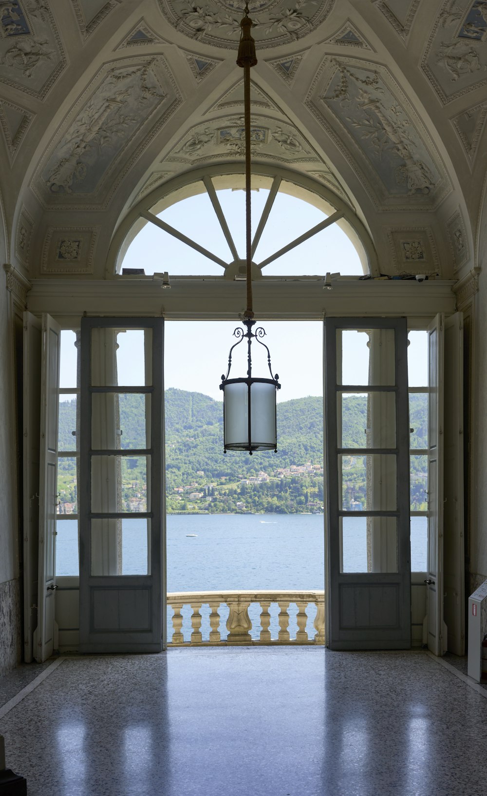 an open door leading to a balcony with a view of a lake