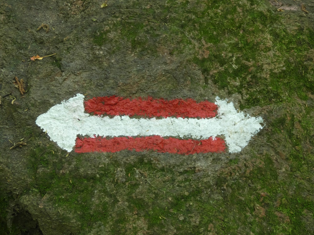 a red and white arrow painted on a rock