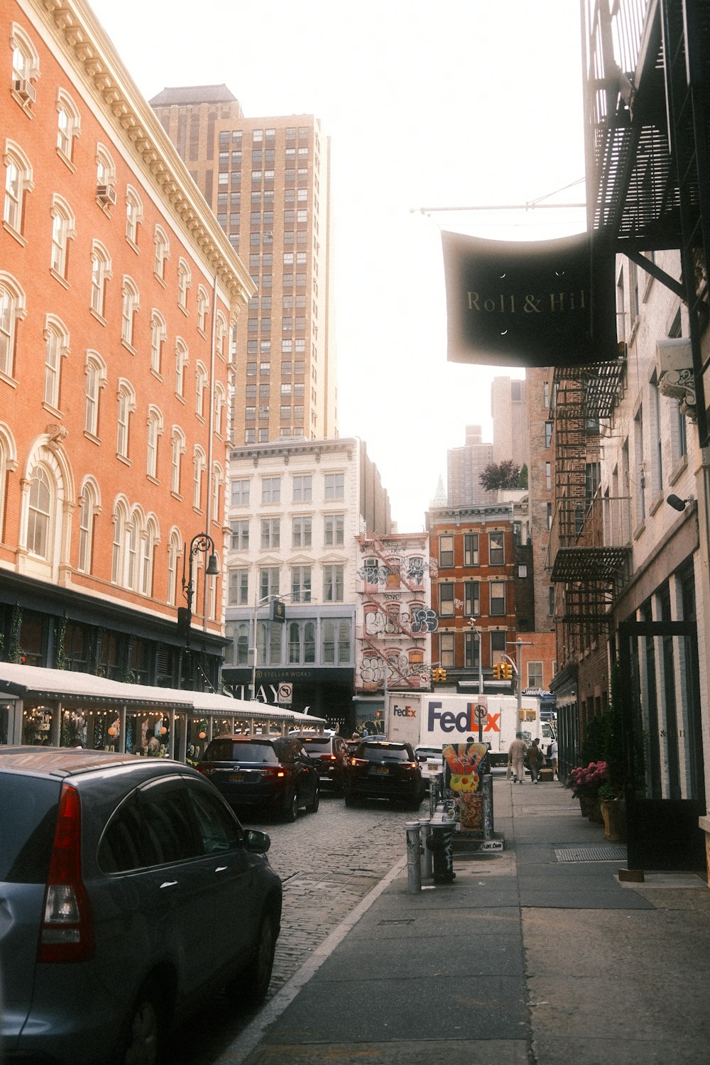 a city street lined with parked cars and tall buildings