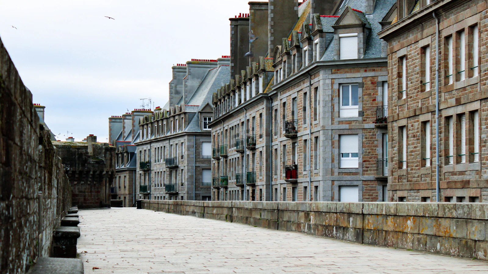 Rue pavée bordée de maisons de pierre dans Saint-Malo intra-muros — photo Matheus Cavaleiro / Unsplash
