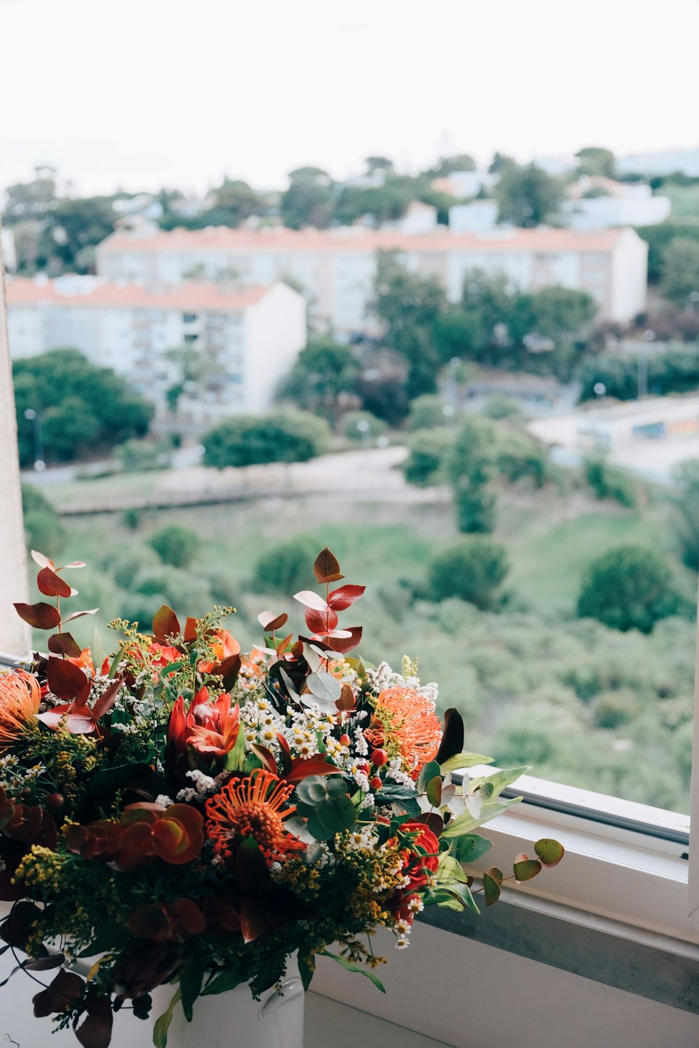 a vase filled with flowers sitting on top of a window sill
