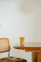 Close-up of a charcoal-colored lounge chair with textured fabric beside a minimalist side table holding a glass of iced tea.