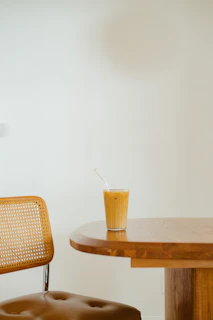 Close-up of a charcoal-colored lounge chair with textured fabric beside a minimalist side table holding a glass of iced tea.