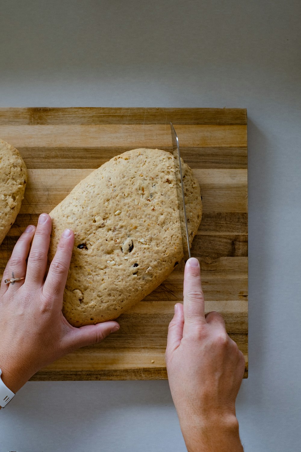 a person cutting a loaf of bread on a cutting board