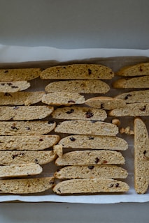 Freshly baked biscotti stacked neatly beside jars of organic ingredients on a sunlit kitchen counter