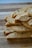 A stack of sliced biscotti placed on a wooden cutting board. The biscotti have a golden-brown color with visible nuts and dried fruit embedded within. The texture appears crunchy and crumbly.