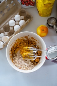 a bowl filled with eggs next to a carton of eggs
