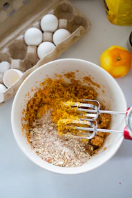 a bowl of food with eggs and a whisk in it