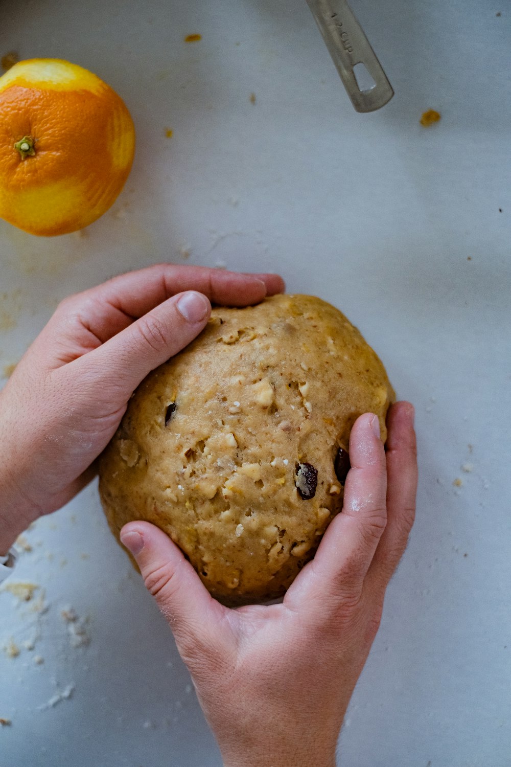 a person holding a cookie in their hands next to an orange