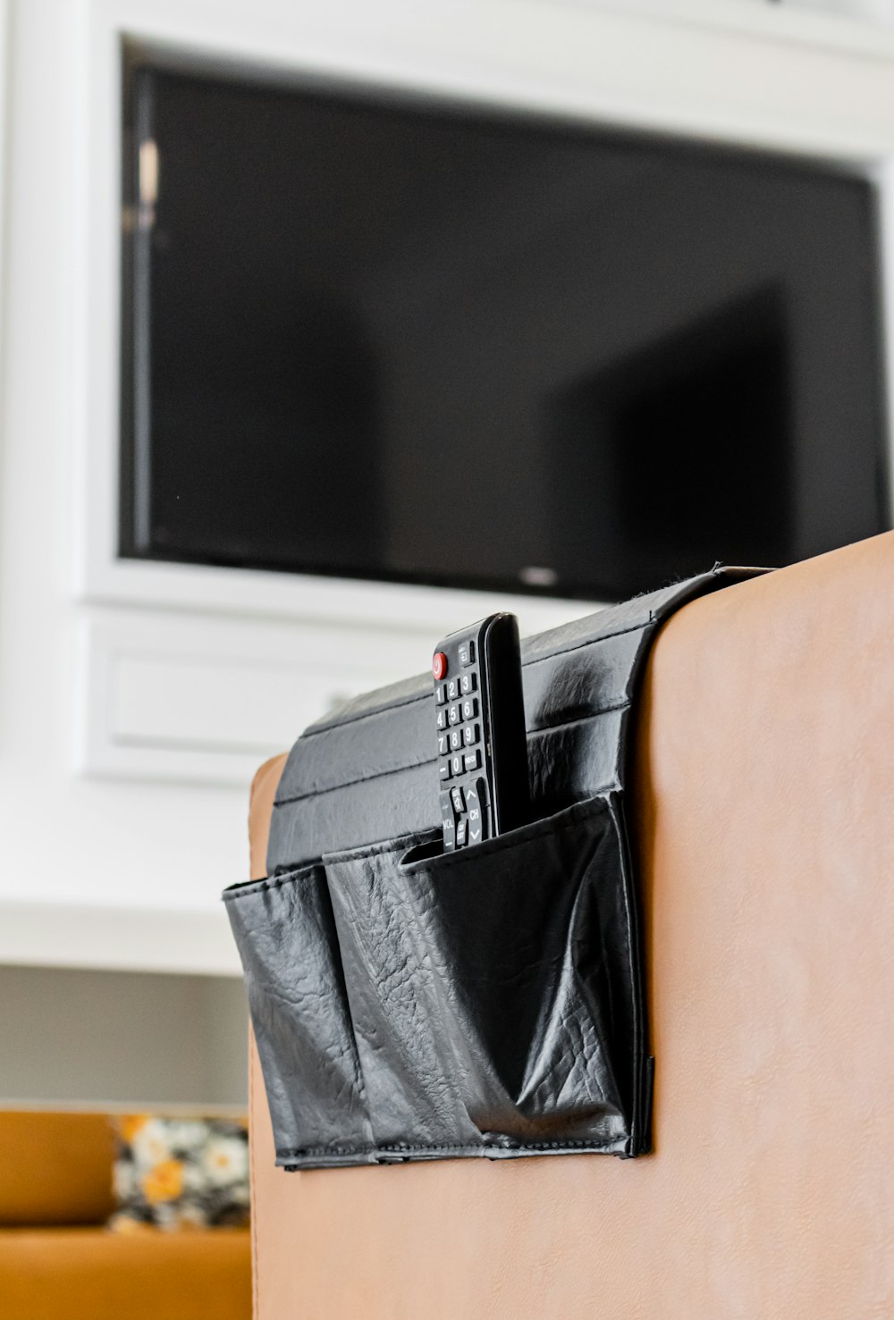 a remote control in a leather pocket in front of a tv