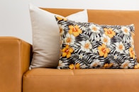 a brown leather couch with a flowered pillow on top of it