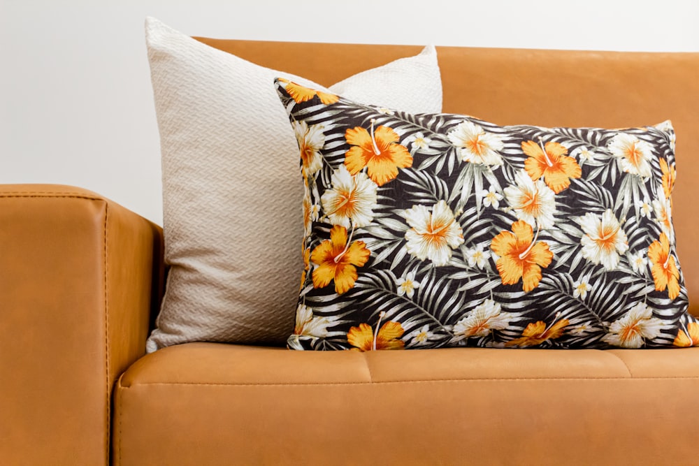 a brown leather couch with a flowered pillow on top of it