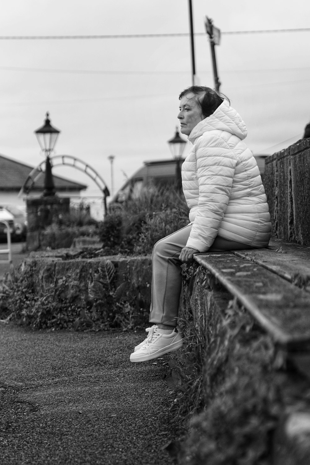 a woman is sitting on a ledge outside