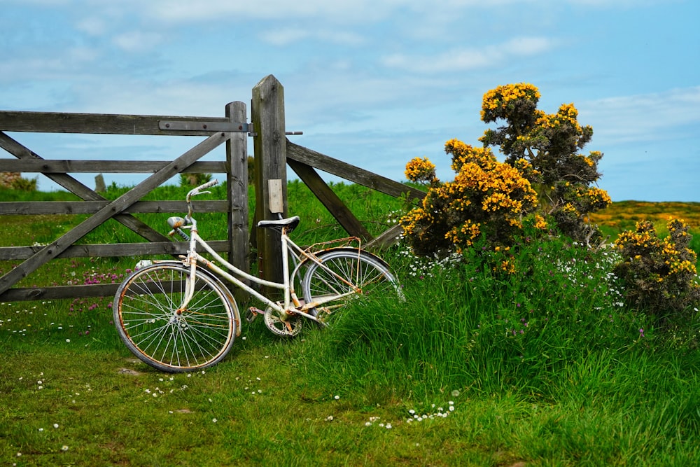 a white bicycle leaning against a wooden fence