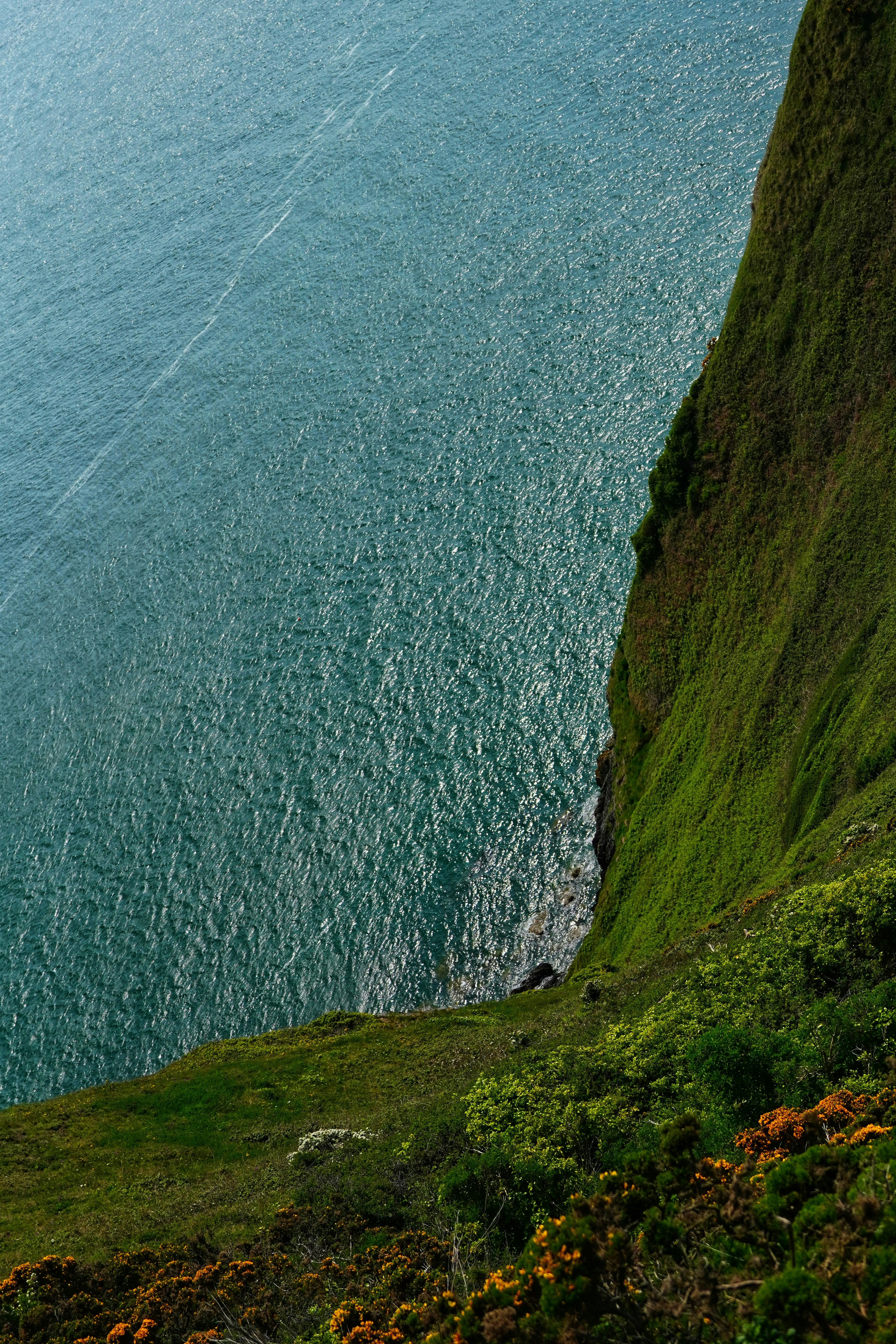 a boat sailing on the ocean near a cliff