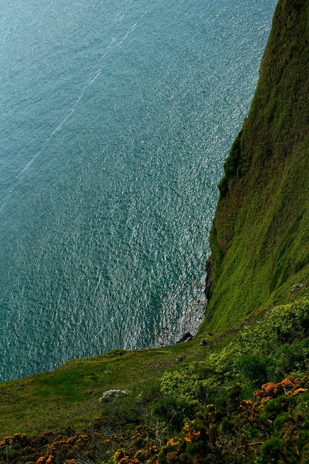a boat sailing on the ocean near a cliff