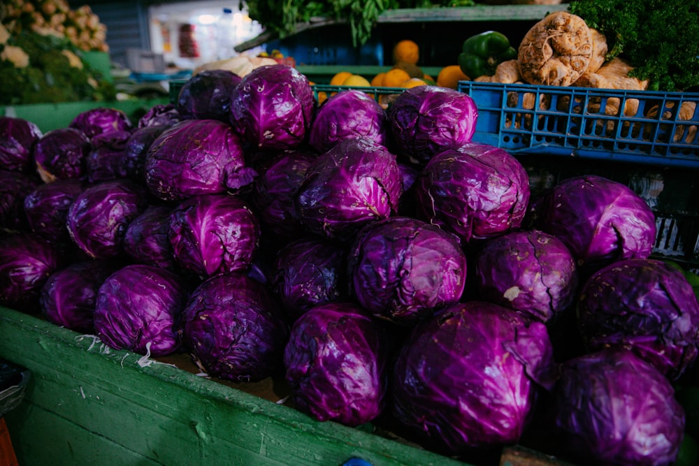 a pile of purple cabbage sitting next to a pile of oranges
