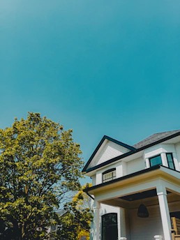 A freshly painted house exterior in sleek black with gold trim under a clear blue sky.