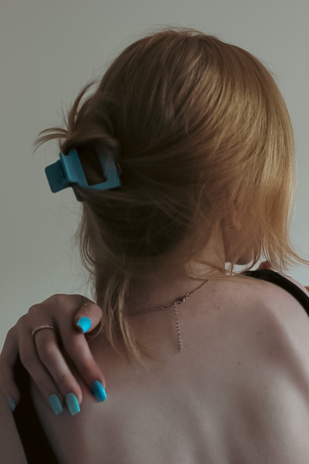 Una mujer con esmalte de uñas azul y un par de gafas en la espalda