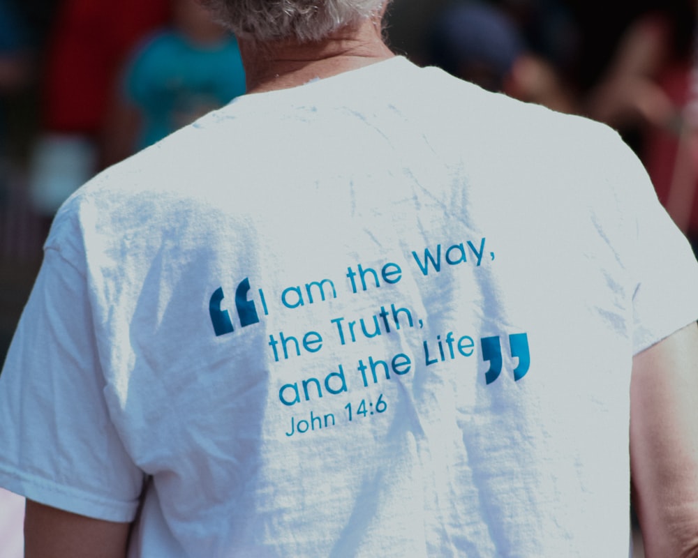 a man wearing a white shirt with a bible verse on it