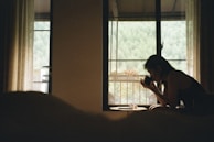 A calm moment of reflection by a window with sheer curtains, showing a leader journaling with a cup of tea nearby.