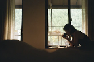 A serene woman sitting peacefully in a sunlit room, journaling with a cup of herbal tea nearby.