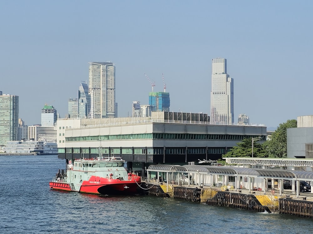 a red and white boat in the water next to a dock