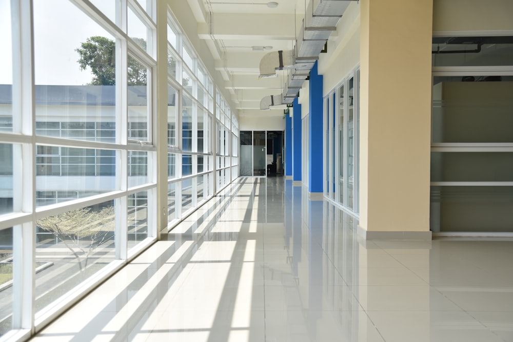 Un largo pasillo con puertas y ventanas azules y blancas