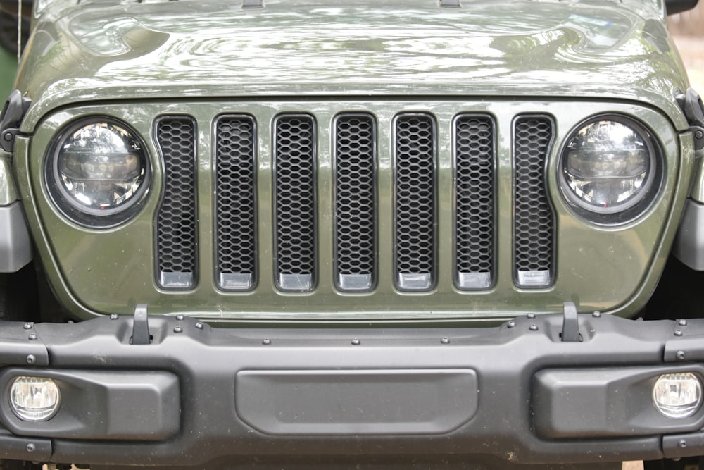 the front of a green jeep with its lights on