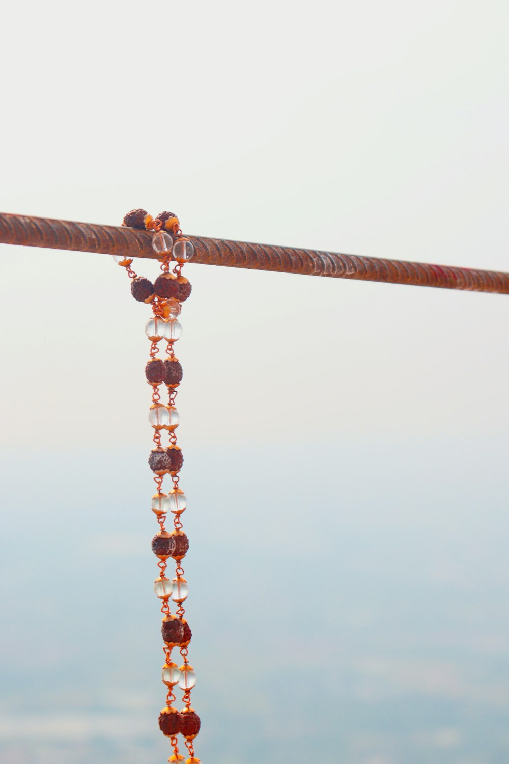 a long beaded necklace hanging from a metal pole