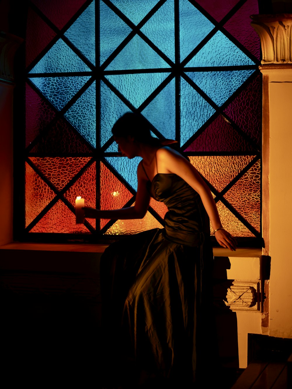 a woman in a black dress standing in front of a stained glass window