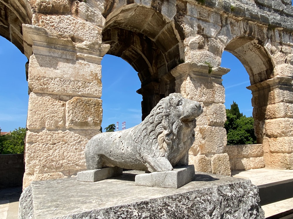 Una estatua de león de piedra frente a un arco de piedra