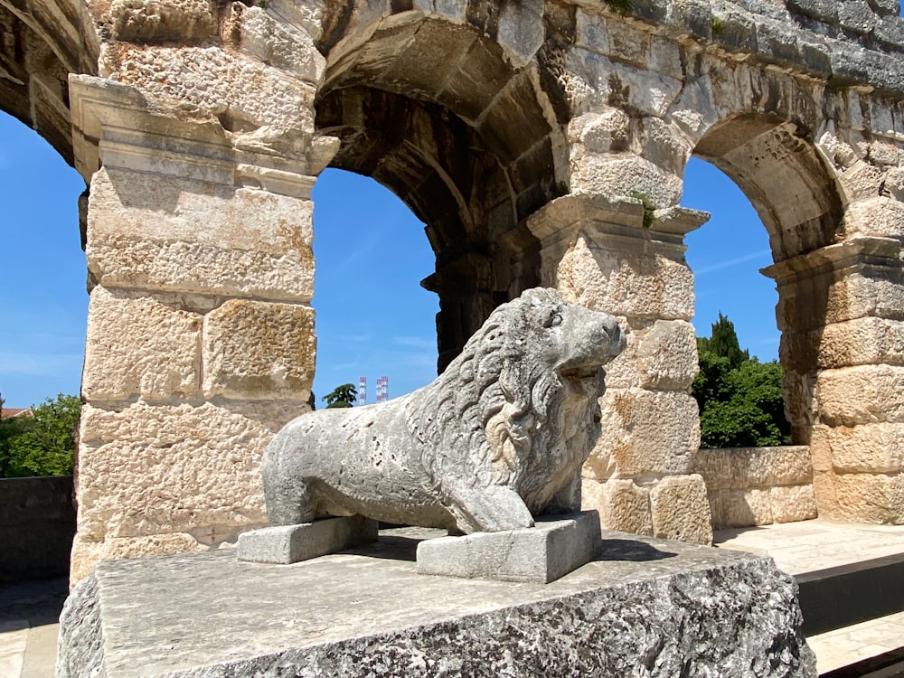 a stone lion statue in front of a stone arch