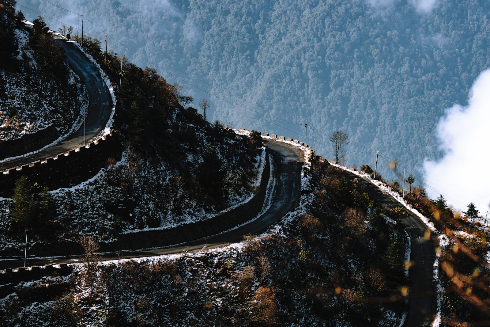 Hairpin bends of the old Silk Route road on a forested hillside dusted with snow at Zuluk, East Sikkim